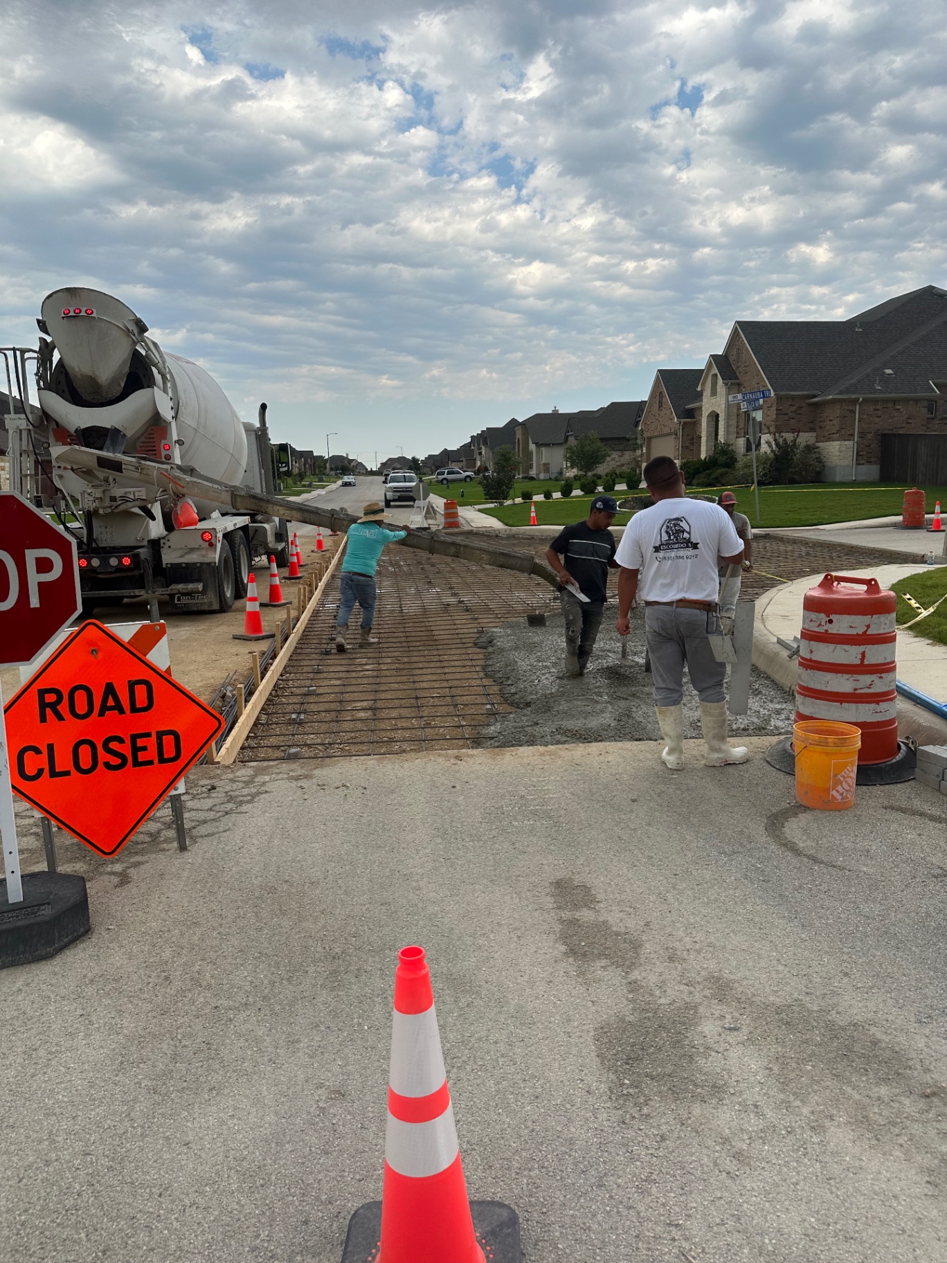 Concrete truck chute feeding a residential street replacement while the City Concrete Construction crew works the pour