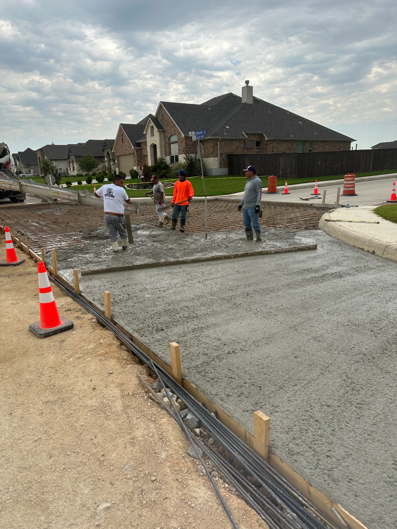 City Concrete Construction crew finishing a reinforced residential street concrete pour with fresh slab in the foreground