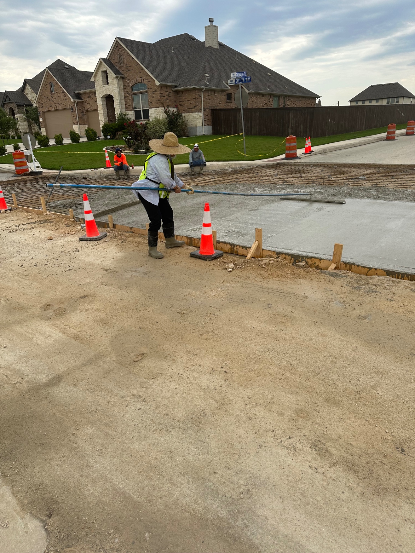 Crew member performing precision finishing on a fresh concrete street slab during a neighborhood infrastructure project